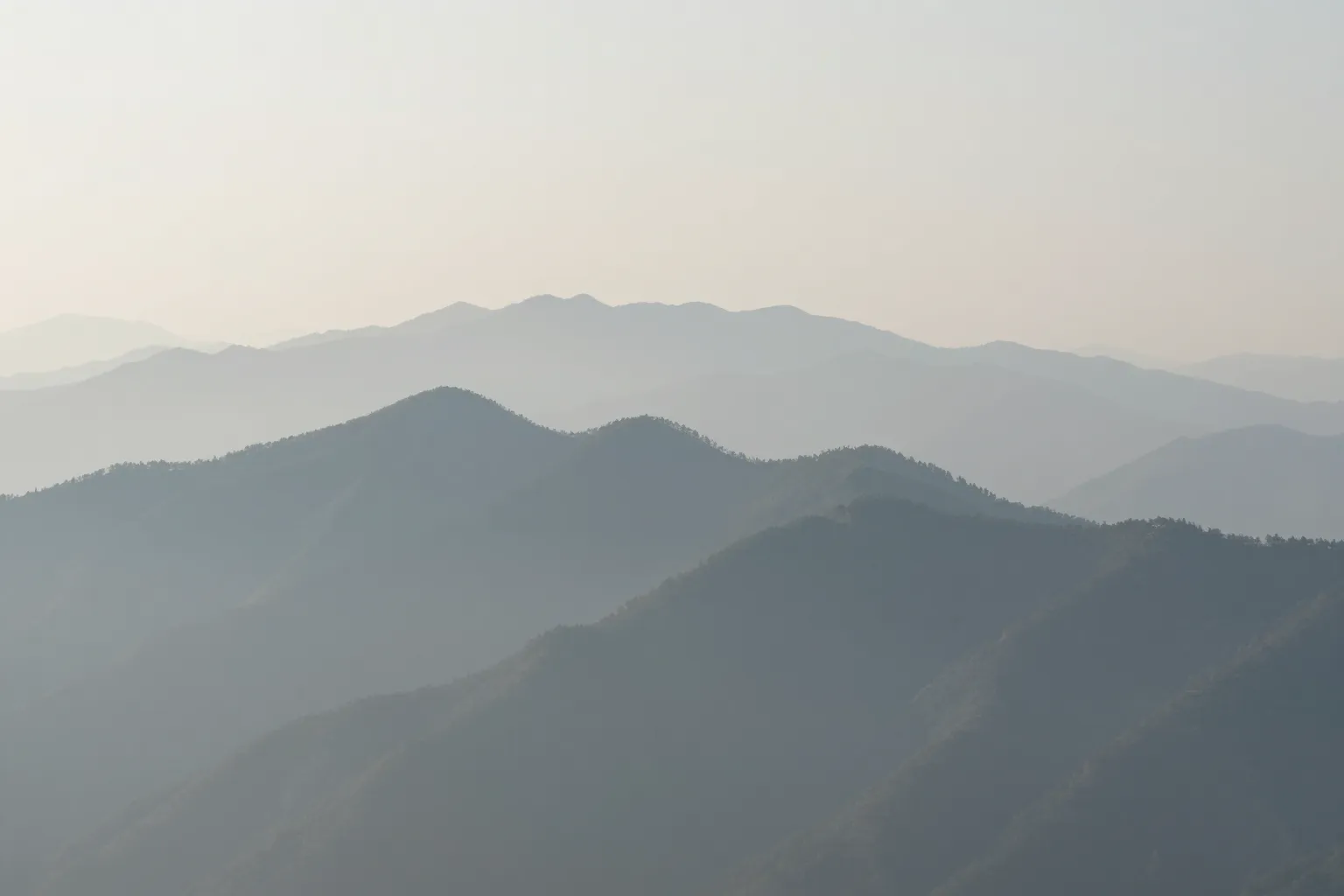 層層山脊在晨霧中一層比一層淡去，最近的一道清楚、遠方的看不清，比喻看得到方向卻無法確認細節